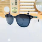 Gros plan sur lunettes clips homme noires rectangulaires en plastique brillant avec détails métalliques et branches fines.