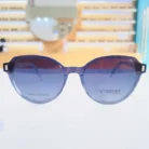 Gros plan de lunettes œil de chat bleues avec verres noirs dégradés et détails rectangulaires aux coins, finition brillante.