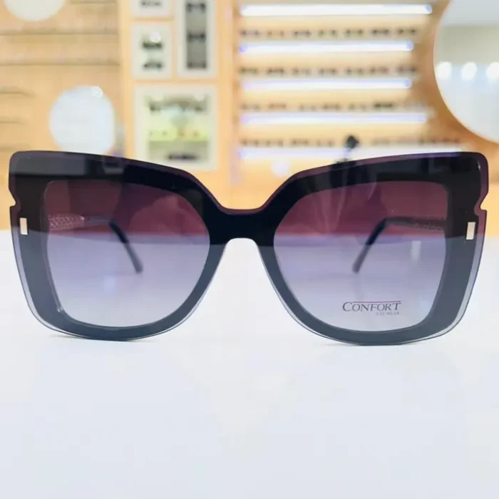 Gros plan sur des lunettes œil de chat noires brillantes, avec touches transparentes et éléments dorés visibles sur la branche.