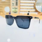 Gros plan sur lunettes rectangulaires noires brillantes avec détails dorés sur les branches, style chic masculin.