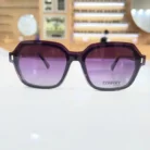 Gros plan sur des lunettes clips rectangulaires violettes avec rivet métallique sur le côté et plastique brillant.