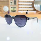 Lunettes bleu foncé portées, monture épaisse brillante avec branches droites et accents dorés, style élégant pour l’extérieur.