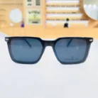 Lunettes clips rectangulaires noires à finition brillante portées en extérieur, style élégant pour un usage quotidien.