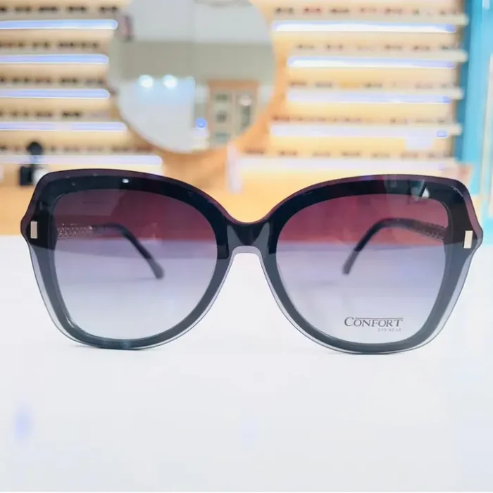 Lunettes de soleil oversize noires en situation, avec légère transparence en bas des verres et éléments métalliques sur les côtés.