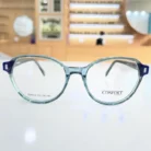 Vue de face de lunettes femme rondes bleu clair, monture plastique brillante avec branches larges et charnières visibles.