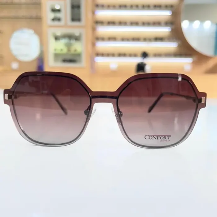 Lunettes géométriques marron foncé portées, monture plastique d’épaisseur moyenne, branches fines et charnières visibles.