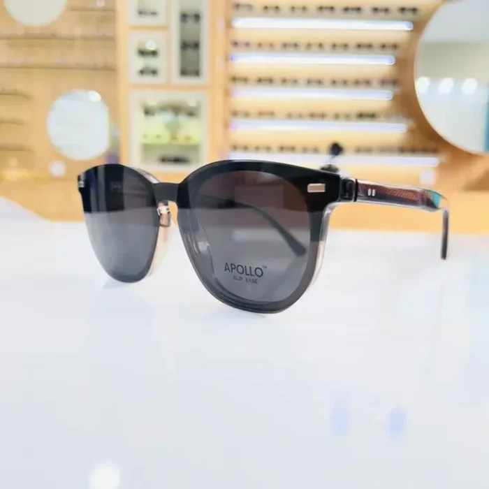 Lunettes homme noires arrondies portées, branches épaisses avec accent doré et verres transparents.