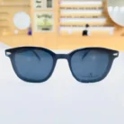 Lunettes homme noires rectangulaires portées en extérieur, monture plastique mate, design épuré pour usage quotidien.