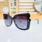 Lunettes œil de chat noires portées, branches dorées texturées visibles, style moderne et élégant pour un look tendance.