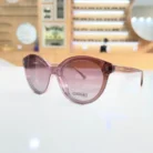 Lunettes œil de chat rose portées, monture plastique brillante aux courbes arrondies et finitions transparentes.