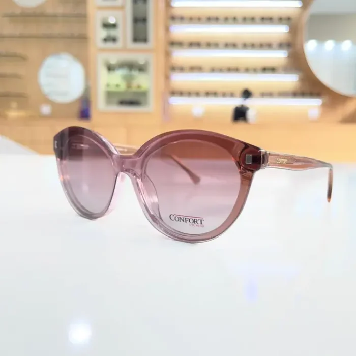 Lunettes œil de chat rose portées, monture plastique brillante aux courbes arrondies et finitions transparentes.