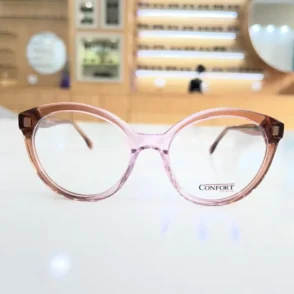Lunettes œil de chat rose transparent avec branches marron, monture plastique brillante vue de face.