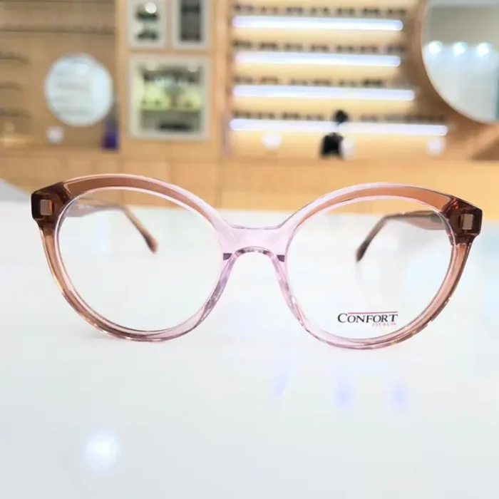 Lunettes œil de chat rose transparent avec branches marron, monture plastique brillante vue de face.