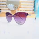 Lunettes œil de chat violet dégradé avec monture épaisse brillante et branches fines, portées en style mode extérieur.
