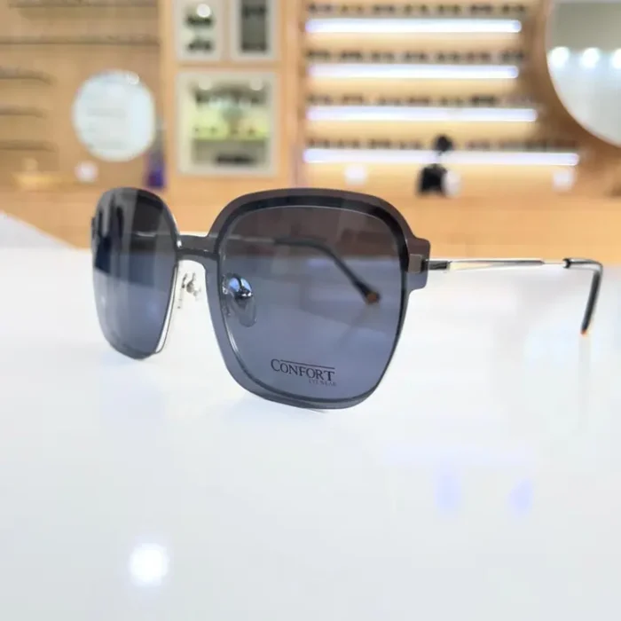 Lunettes oversize noires portées en extérieur, forme carrée avec branches en métal et embouts noirs, style élégant.