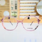 Gros plan sur des lunettes oversize rondes roses brillantes, branches fines avec motifs aux extrémités.