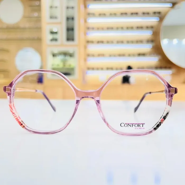Gros plan sur des lunettes oversize rondes roses brillantes, branches fines avec motifs aux extrémités.