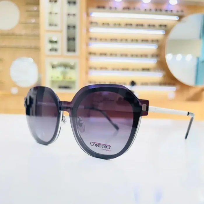 Gros plan de lunettes oversize rondes violet foncé, finition brillante, branches fines avec extrémités blanches.