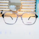 Vue de face de lunettes rectangulaires transparentes à monture fine et branches noires, finition brillante.