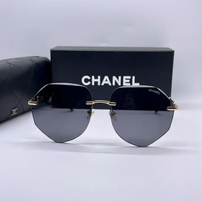 Chanel lunettes de soleil à verres octogonaux teintés, sans monture, avec branches fines dorées et boîte CHANEL en arrière-plan.