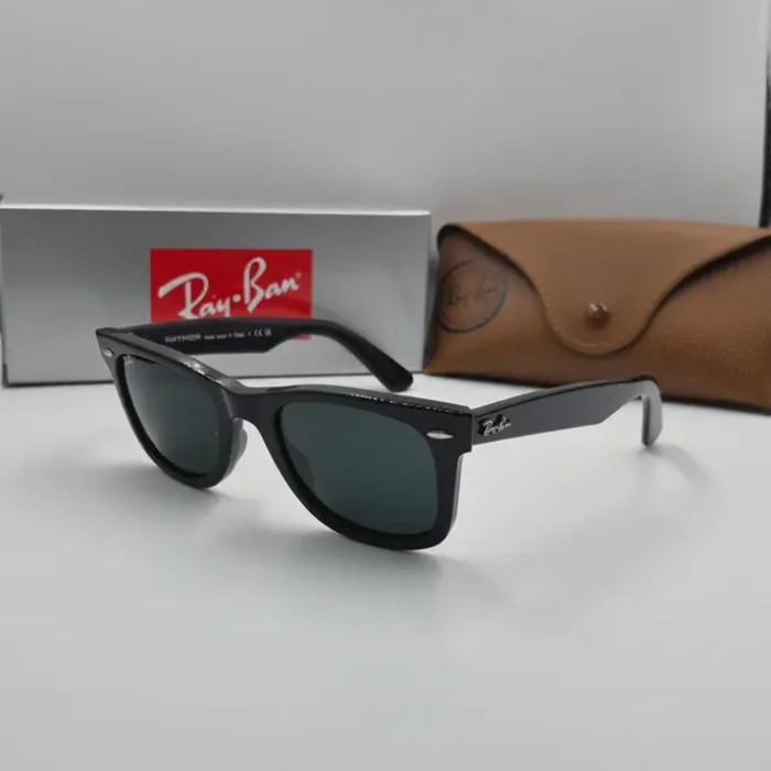 Les lunette de soleil à monture noire et verres teintés, posées avec un étui et une boîte marron de protection.