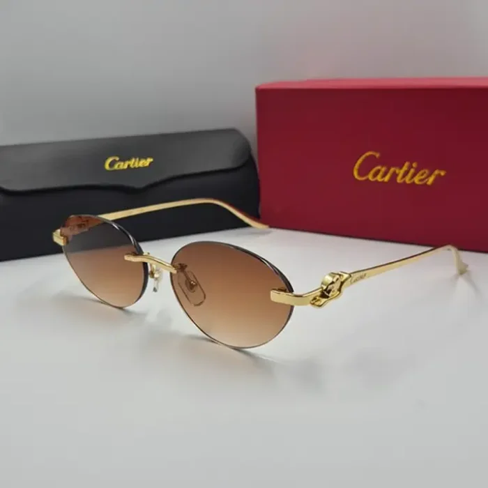 Lunette de soleil Cartier femme panthere dorée Lunette de soleil Cartier femme panthere avec branches dorées motif panthère et verres bruns dégradés, posée devant des étuis.