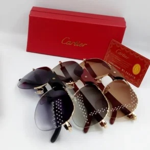 Plusieurs paires de lunette de soleil Cartier homme en métal doré, verres teintés noir et brun, près d’une boîte rouge Cartier.