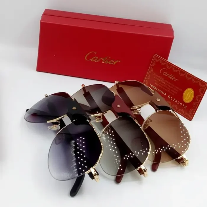 Lunette de soleil Cartier homme dorée métal Plusieurs paires de lunette de soleil Cartier homme en métal doré, verres teintés noir et brun, près d’une boîte rouge Cartier.