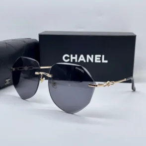 Lunette de soleil Chanel femme avec verres teintés sombres légèrement octogonaux, branches dorées et boîte noire Chanel.