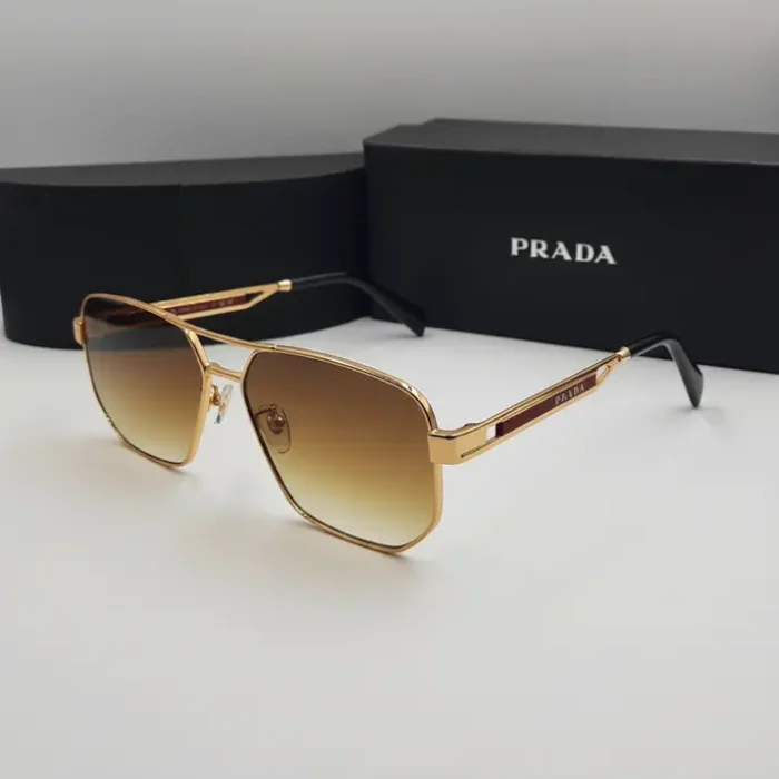 Lunette de soleil Prada homme métal doré Lunette de soleil Prada homme avec monture en métal doré, verres rectangulaires dégradés marron et embouts noirs.