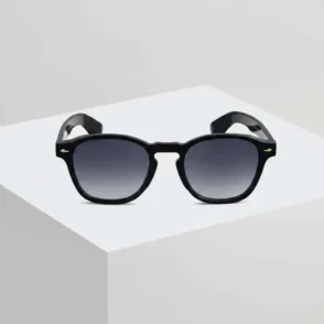 Lunette de soleil noir avec monture noire épaisse, verres teintés et détails métalliques dorés près des charnières.