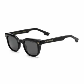 Tendance lunette de soleil homme à monture noire robuste, forme rectangulaire, verres teintés foncés et détail doré sur la branche.