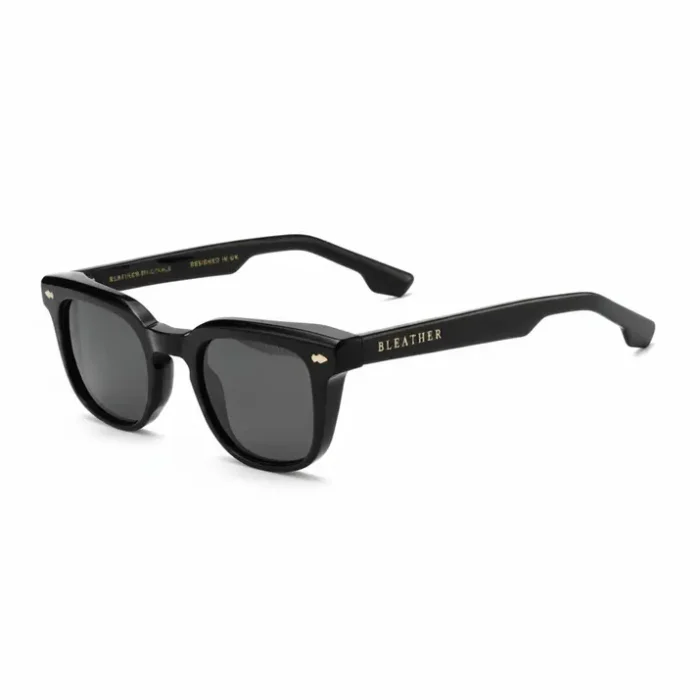 Tendance lunette de soleil homme noir rectangulaire Tendance lunette de soleil homme à monture noire robuste, forme rectangulaire, verres teintés foncés et détail doré sur la branche.