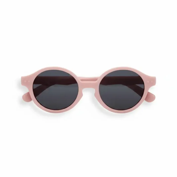 Paire de Izipizi lunettes de soleil à monture rose pâle, verres ronds foncés et branches épaisses aux extrémités arrondies.