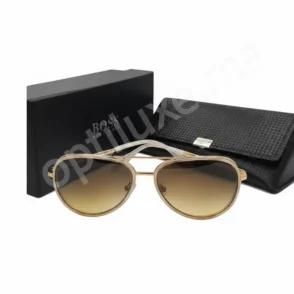 Lunette de soleil Hugo Boss femme à monture métal doré, verres aviator dégradés marron, avec étui et boîte BOSS en fond.