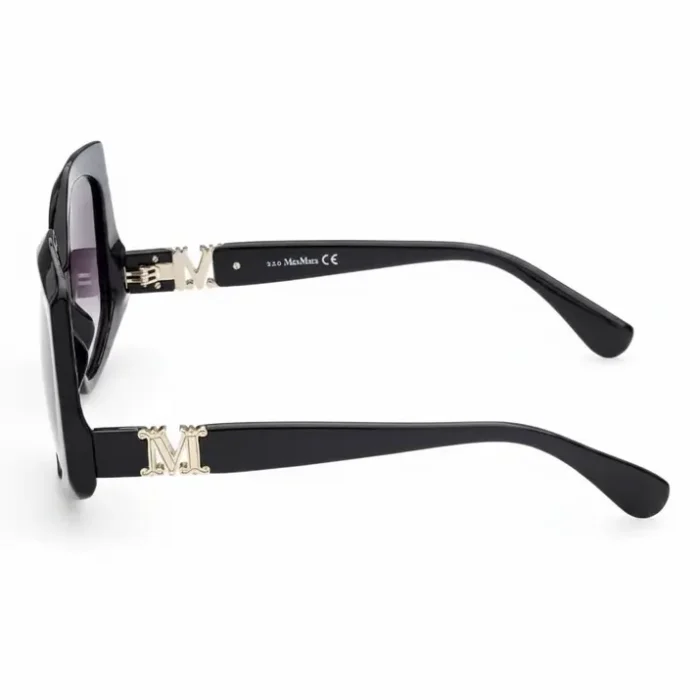 Lunette de soleil femme noir avec monture noire, verres foncés et branches épaisses ornées d’un M doré.