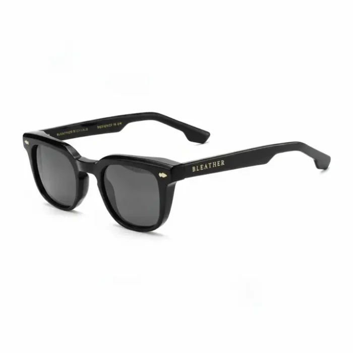 Lunette de soleil homme mode noire à monture épaisse rectangulaire, verres teintés foncés et branches avec inscription dorée.
