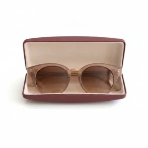Lunette de soleil marron à verres teintés marron posée dans un étui bordeaux ouvert, monture ronde.