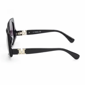 Lunette de soleil opticien à monture épaisse noire, verres teintés et détails métalliques dorés en forme de M sur les branches.