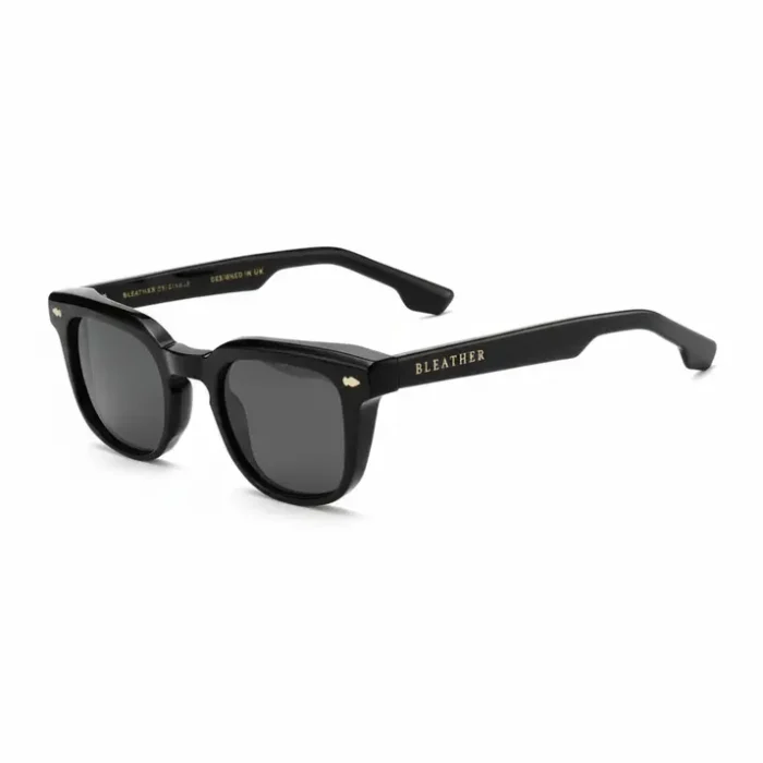 Lunette de soleil pour homme noire style classique Lunette de soleil pour homme noire brillante, verres rectangulaires foncés et branches épaisses avec inscriptions dorées.