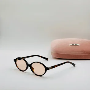 Lunette de vue Miu Miu à monture écaille brun et noir, verres ovales légèrement teintés, avec étui rose.